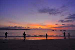 silhouette of five people standing on seashore during sunset